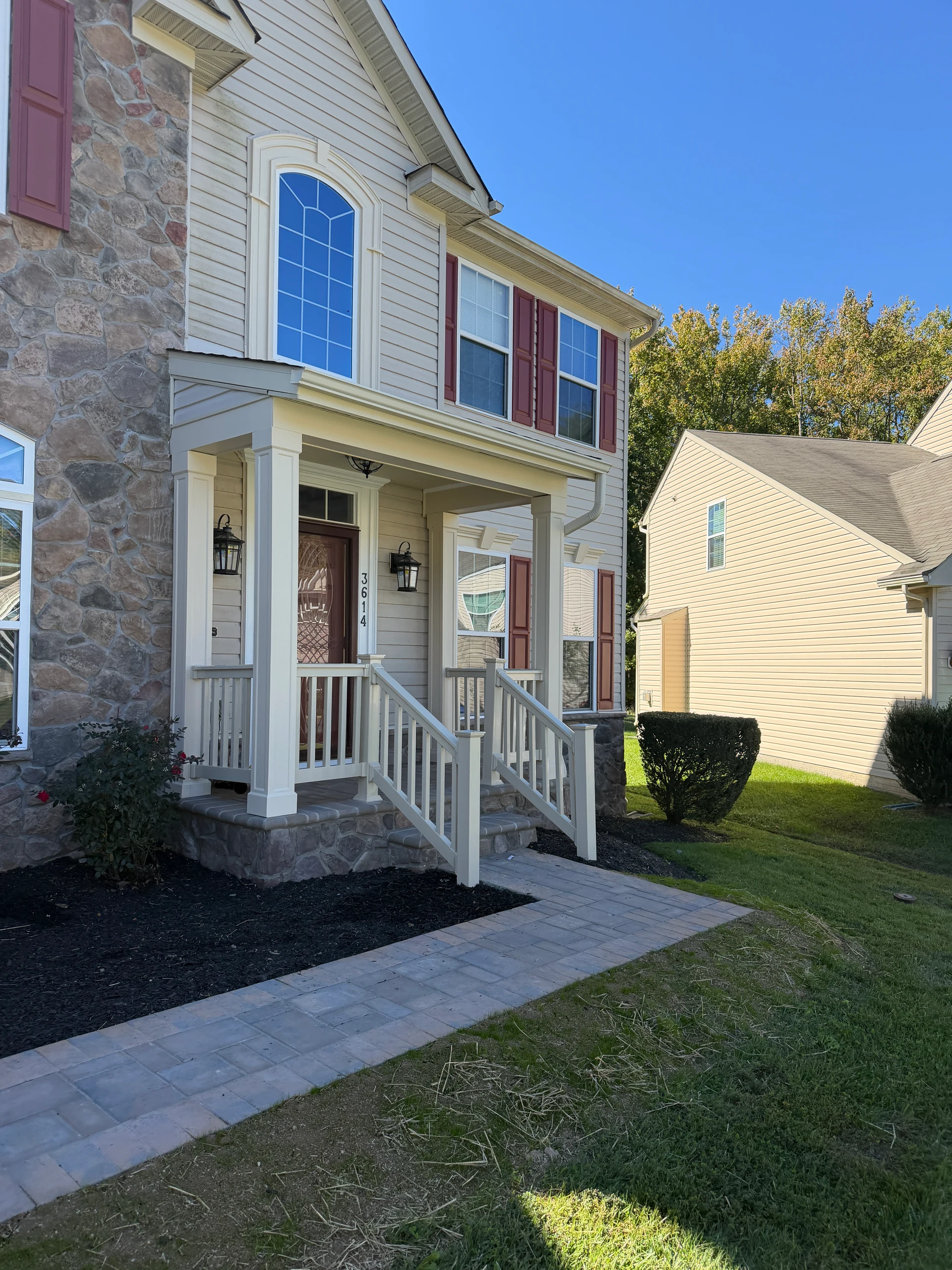 Front porch with white columns, railings and a stone base