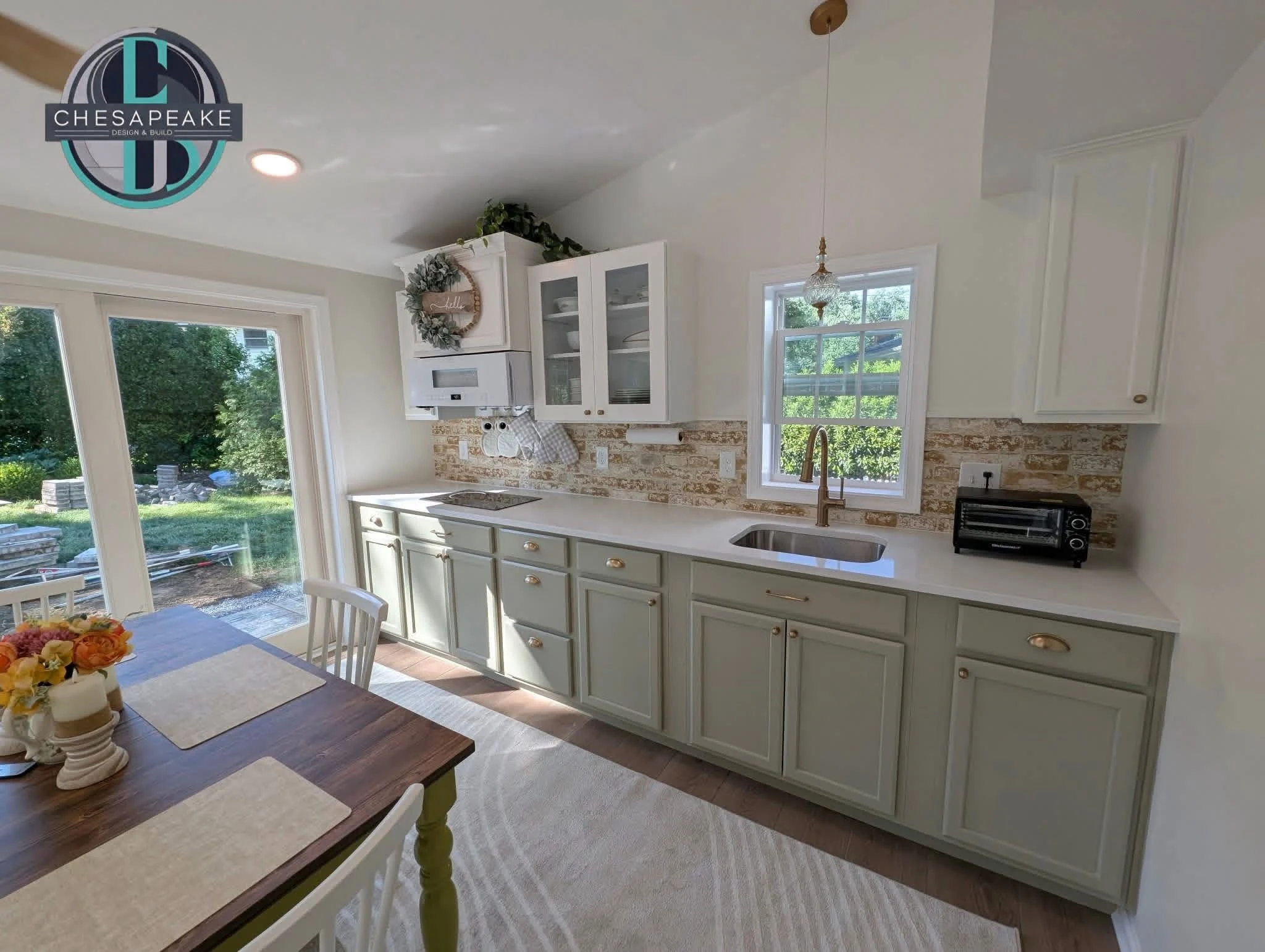 Kitchen with light cabinetry, brass hardware and a brick backsplash